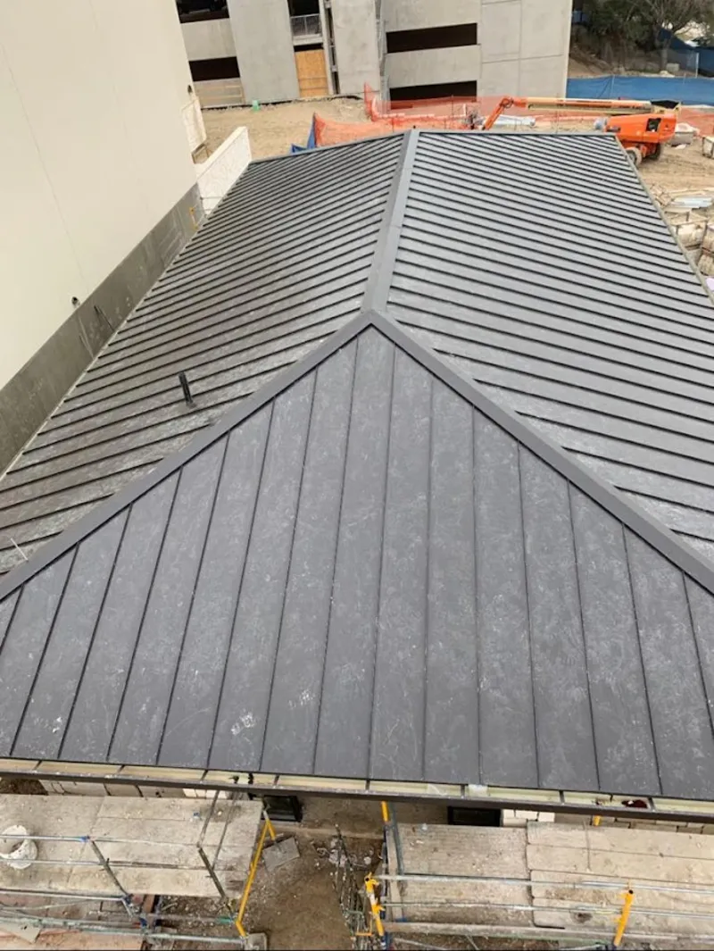 Commercial metal roof construction with crane equipment in Mead